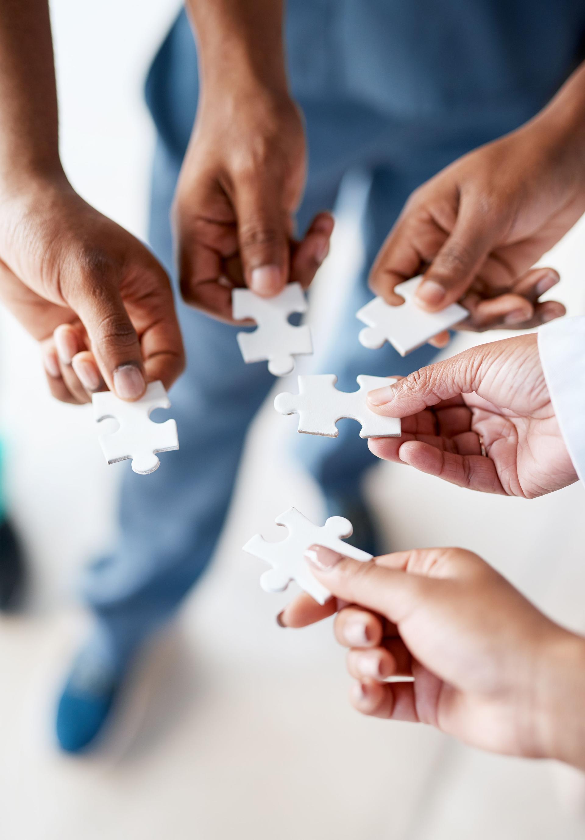 Hands, puzzle pieces and business, planning or teamwork on project in office with group collaboration. Cooperation, support team and people with jigsaw for innovation, solution and problem solving.